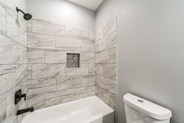 bathroom with toilet and tiled shower / bath