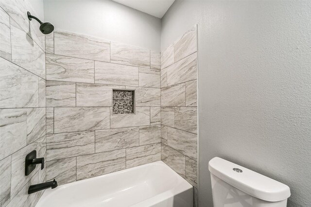 bathroom featuring tiled shower / bath combo and toilet