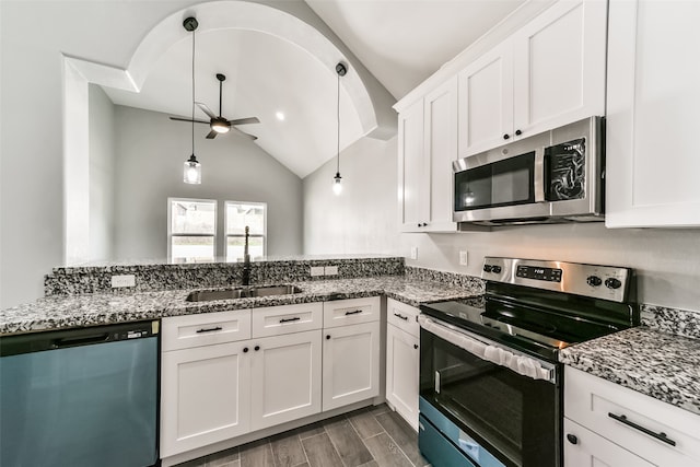 kitchen featuring vaulted ceiling, ceiling fan, appliances with stainless steel finishes, decorative light fixtures, and white cabinetry