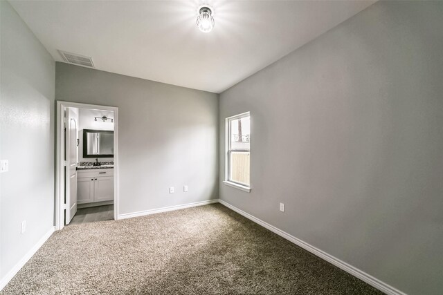 unfurnished bedroom with light colored carpet and connected bathroom