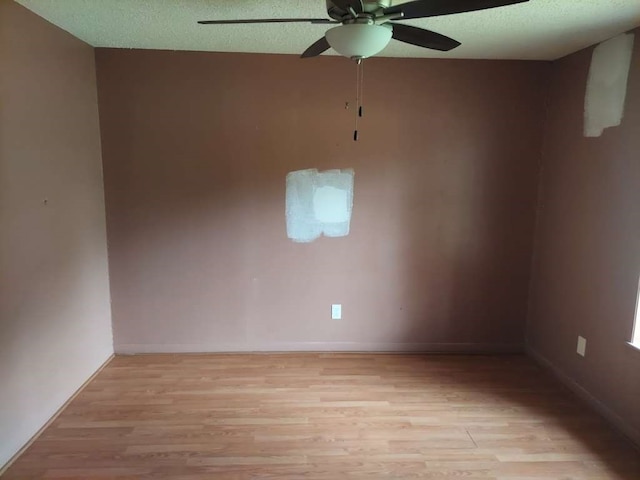 empty room featuring ceiling fan, light wood-type flooring, and a textured ceiling