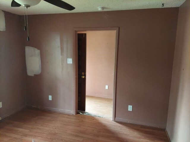 empty room with ceiling fan, light hardwood / wood-style flooring, and a textured ceiling