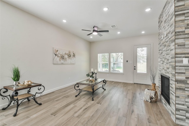 living area featuring a fireplace, light hardwood / wood-style floors, and ceiling fan