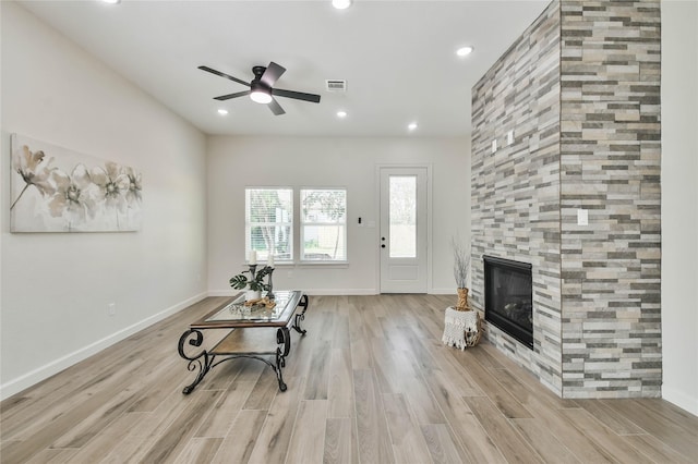 living room with ceiling fan, a fireplace, and light hardwood / wood-style floors