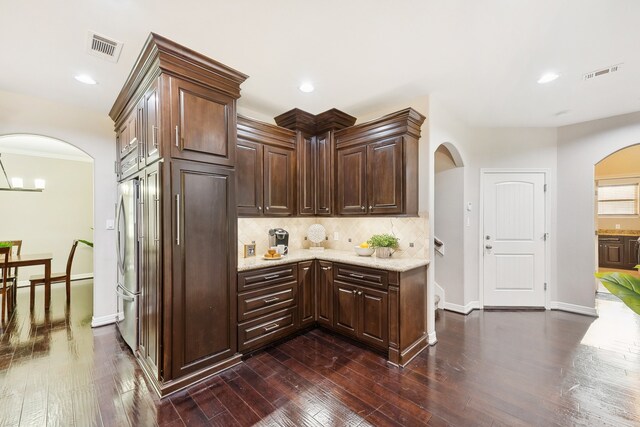 kitchen with backsplash, dark hardwood / wood-style flooring, dark brown cabinetry, and light stone counters