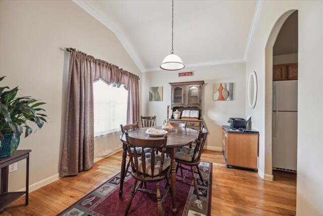 dining room with lofted ceiling, crown molding, and light wood-type flooring