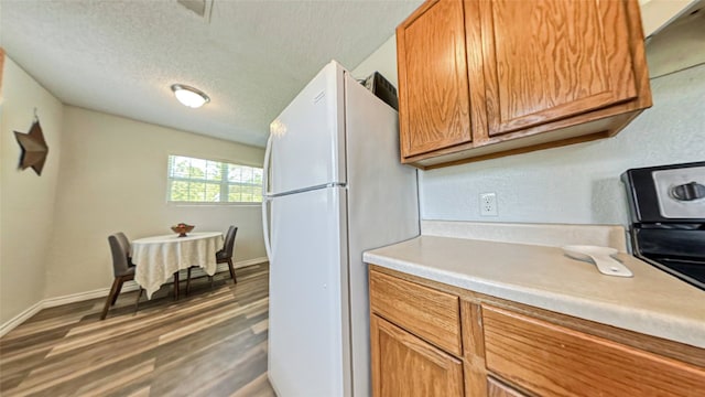 kitchen featuring white fridge, a textured ceiling, and dark hardwood / wood-style flooring