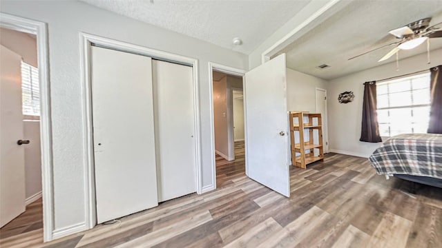 bedroom with a closet, hardwood / wood-style floors, a textured ceiling, and ceiling fan