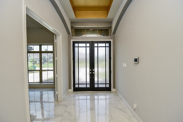 tiled foyer featuring french doors and a raised ceiling