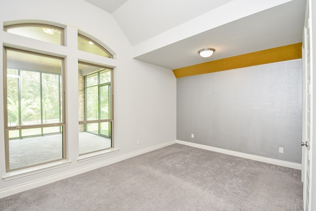 carpeted empty room featuring lofted ceiling