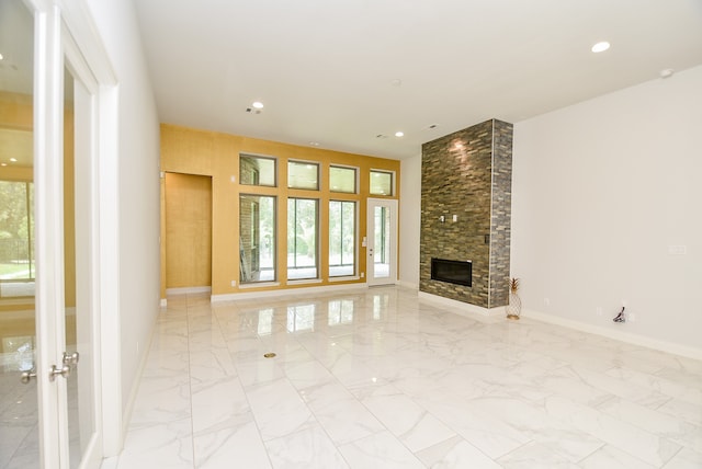 unfurnished living room featuring french doors, a stone fireplace, and light tile patterned floors