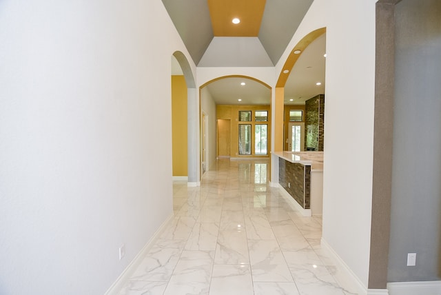 hallway with high vaulted ceiling and light tile patterned floors