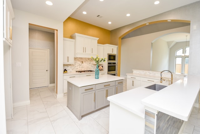 kitchen with stainless steel appliances, light tile patterned floors, decorative backsplash, sink, and a center island