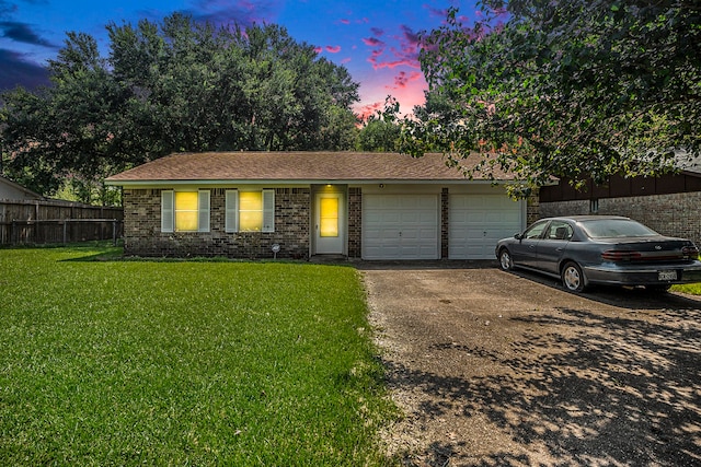 ranch-style house featuring a garage and a yard