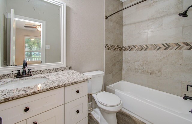 full bathroom featuring toilet, vanity, tiled shower / bath, hardwood / wood-style flooring, and ceiling fan