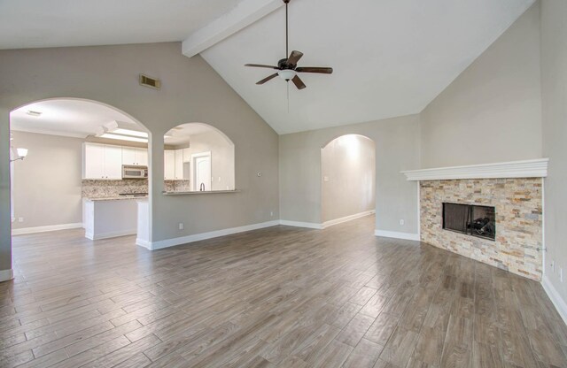 unfurnished living room with high vaulted ceiling, wood-type flooring, ceiling fan, beam ceiling, and a fireplace