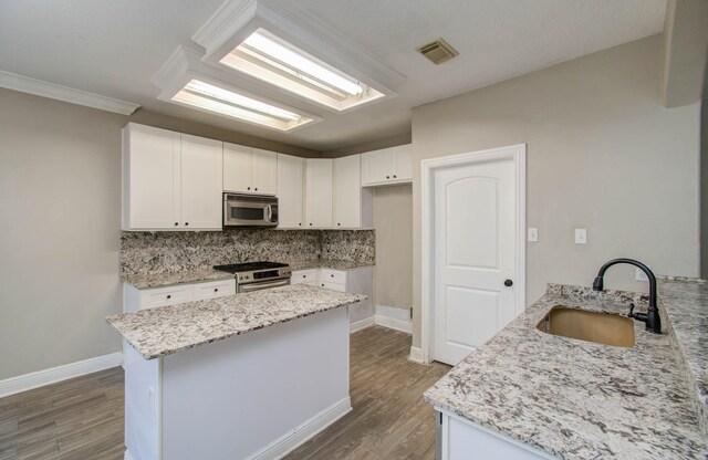 kitchen with appliances with stainless steel finishes, sink, light stone countertops, and decorative backsplash