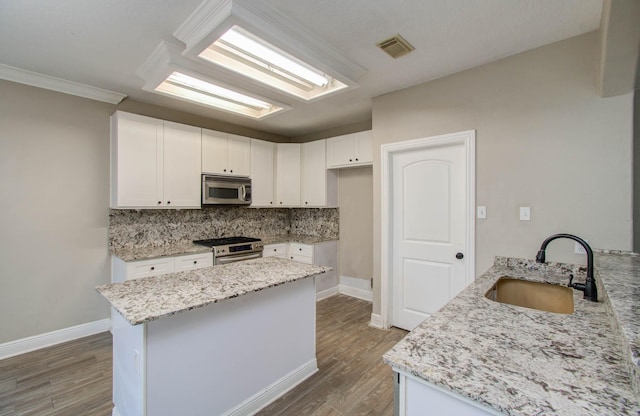 kitchen with white cabinetry, stainless steel appliances, light stone countertops, and sink