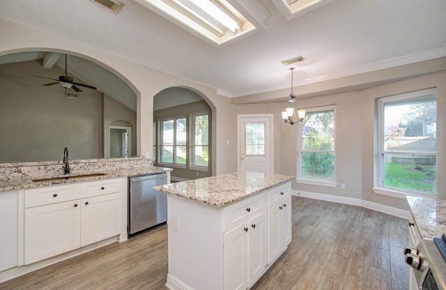 kitchen with sink, dishwasher, light stone counters, white cabinets, and a kitchen island