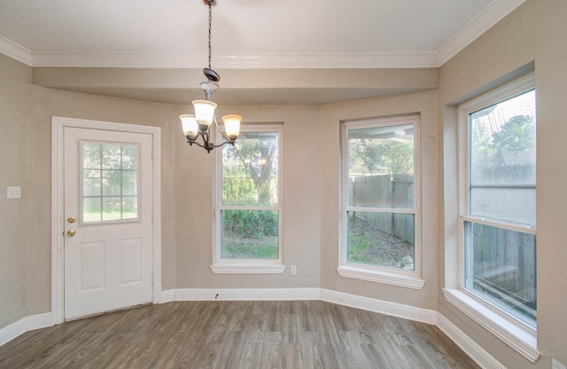 unfurnished dining area with crown molding, hardwood / wood-style flooring, and a chandelier