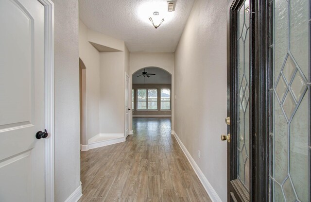 hall featuring a textured ceiling and light hardwood / wood-style floors