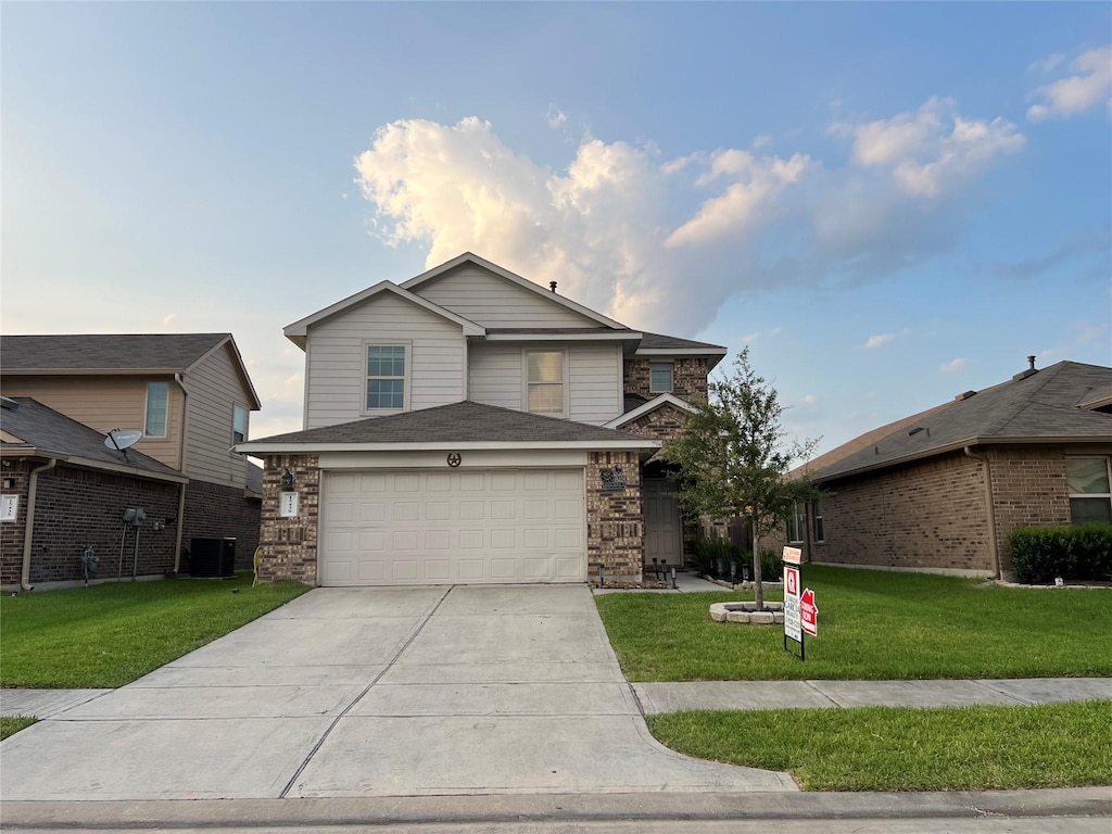 front facade featuring a front yard, a garage, and central air condition unit