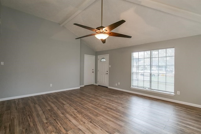 empty room featuring vaulted ceiling with beams, hardwood / wood-style floors, ceiling fan, and a wealth of natural light