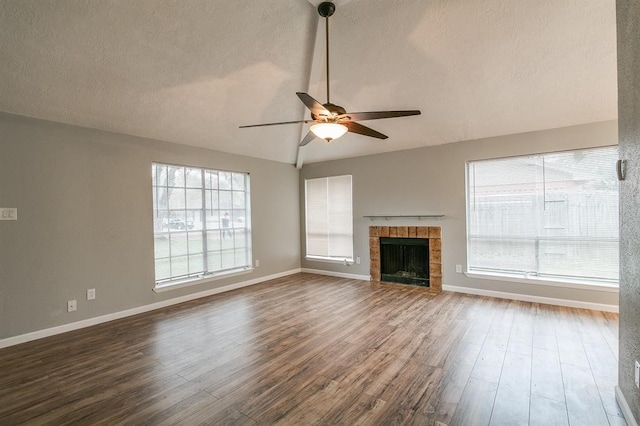 unfurnished living room featuring ceiling fan, a fireplace, vaulted ceiling, and hardwood / wood-style flooring