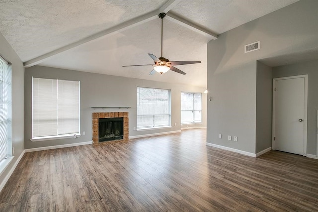 unfurnished living room with a tile fireplace, lofted ceiling with beams, ceiling fan, and hardwood / wood-style flooring