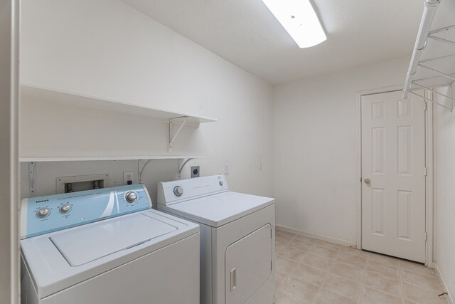 laundry area with light tile patterned floors and washing machine and clothes dryer