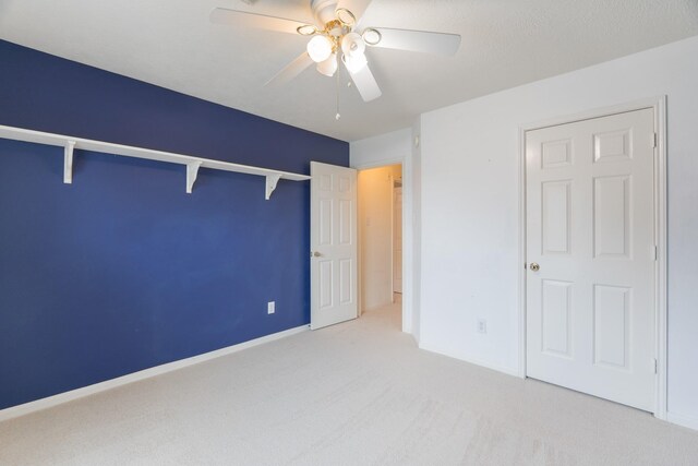 unfurnished bedroom featuring light carpet, a closet, and ceiling fan