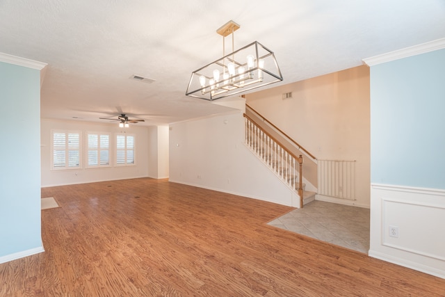 unfurnished living room featuring ceiling fan with notable chandelier, ornamental molding, and light hardwood / wood-style floors