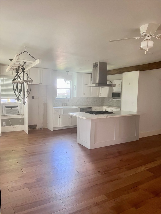 kitchen featuring island range hood, ceiling fan with notable chandelier, light hardwood / wood-style floors, and white cabinetry