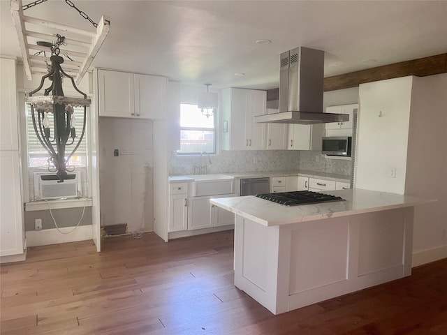 kitchen featuring appliances with stainless steel finishes, white cabinets, range hood, light hardwood / wood-style floors, and sink