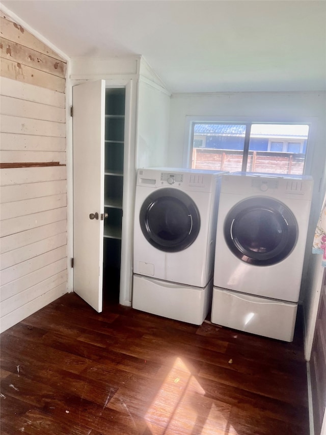 clothes washing area with wood walls, separate washer and dryer, and hardwood / wood-style flooring