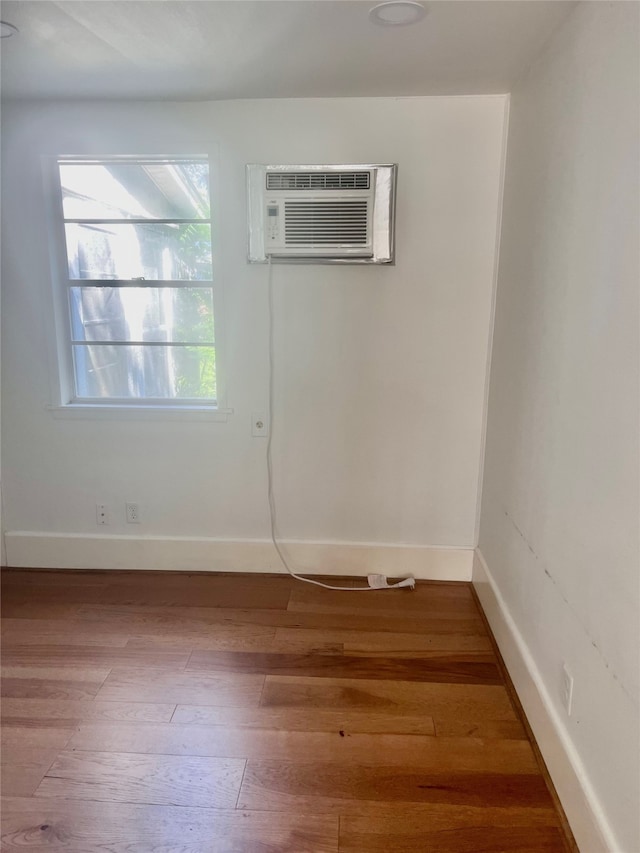 empty room featuring an AC wall unit and wood-type flooring