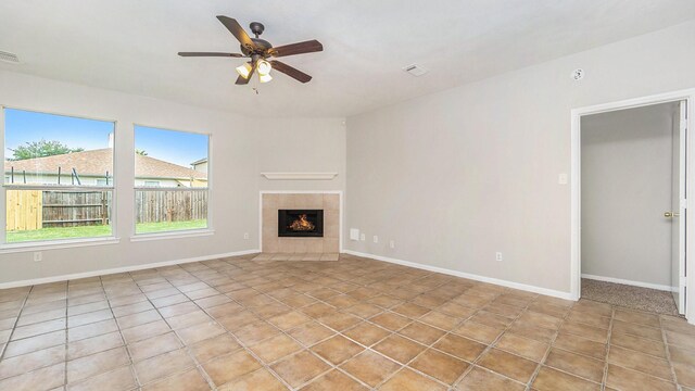 unfurnished living room with ceiling fan, light tile patterned floors, and a tile fireplace