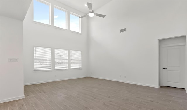 unfurnished living room with ceiling fan, a healthy amount of sunlight, high vaulted ceiling, and light wood-type flooring