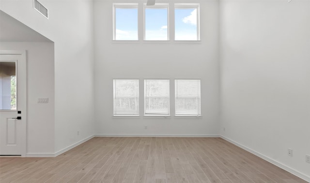 empty room featuring a towering ceiling and light hardwood / wood-style floors