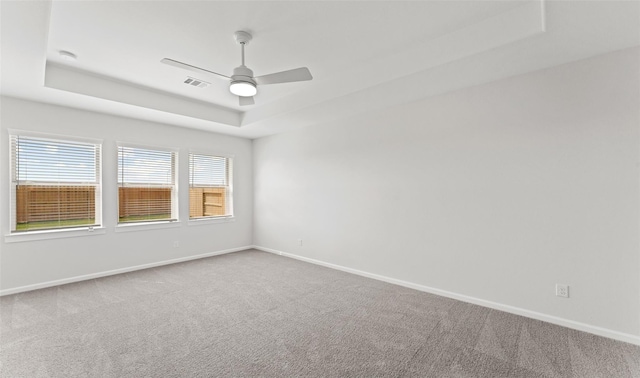 carpeted spare room with ceiling fan and a tray ceiling