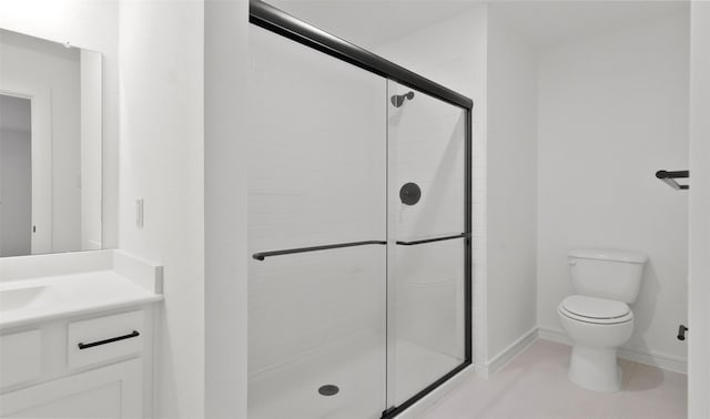 bathroom featuring a shower with door, vanity, tile patterned floors, and toilet