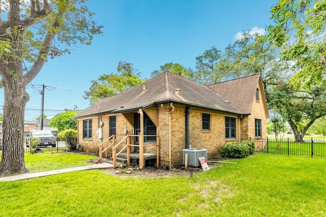 back of property featuring central AC and a yard