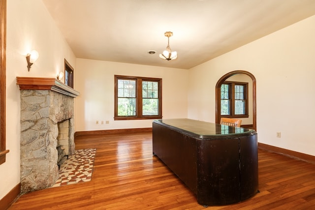 home office featuring a fireplace, an inviting chandelier, and wood-type flooring