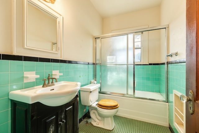 full bathroom with tile walls, toilet, tile patterned floors, vanity, and enclosed tub / shower combo