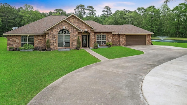 ranch-style house with roof with shingles, a lawn, and brick siding