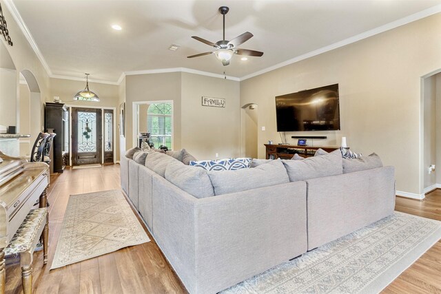 living room featuring light hardwood / wood-style flooring, ornamental molding, and ceiling fan