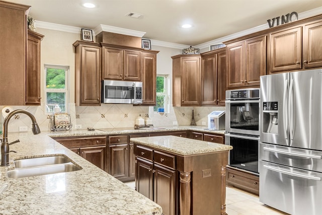 kitchen featuring light stone counters, appliances with stainless steel finishes, sink, and backsplash