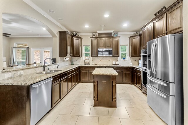 kitchen with light tile patterned flooring, stainless steel appliances, backsplash, a center island, and kitchen peninsula