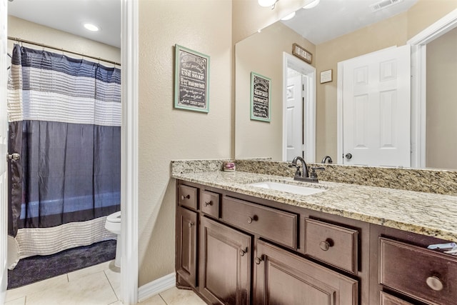 bathroom with toilet, vanity, and tile patterned flooring