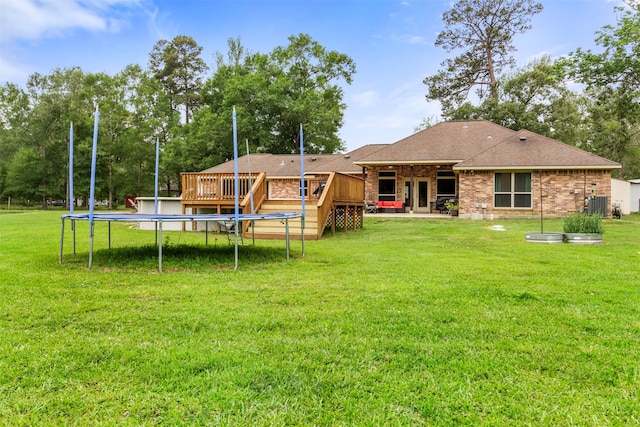 back of property with a yard, a trampoline, and a deck